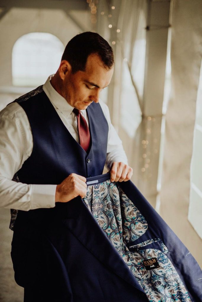 Man in custom vest donning a custom jacket with paisley lining.