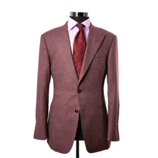 A wine colored suit jacket on a body form with a light pink shirt and a red on red pattered tie on a white background