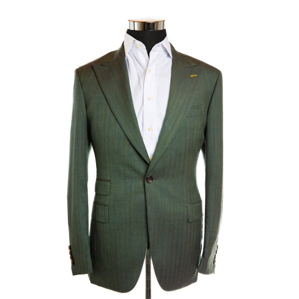 A forest green suit jacket on a body form with a white shirt on a white background