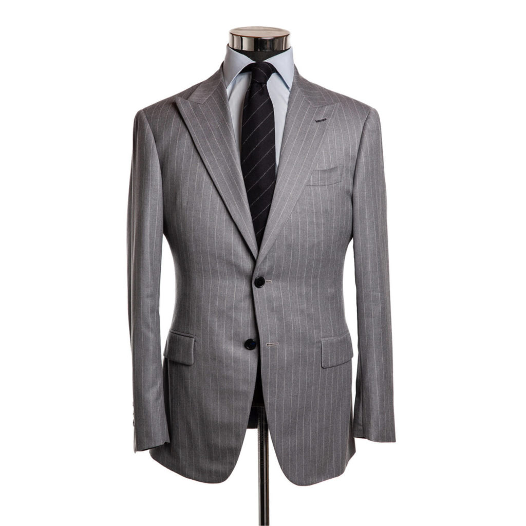 A light grey suit jacket with white pinstripes, on a body form with a very light grey shirt and black tie with grey stripes on a white background