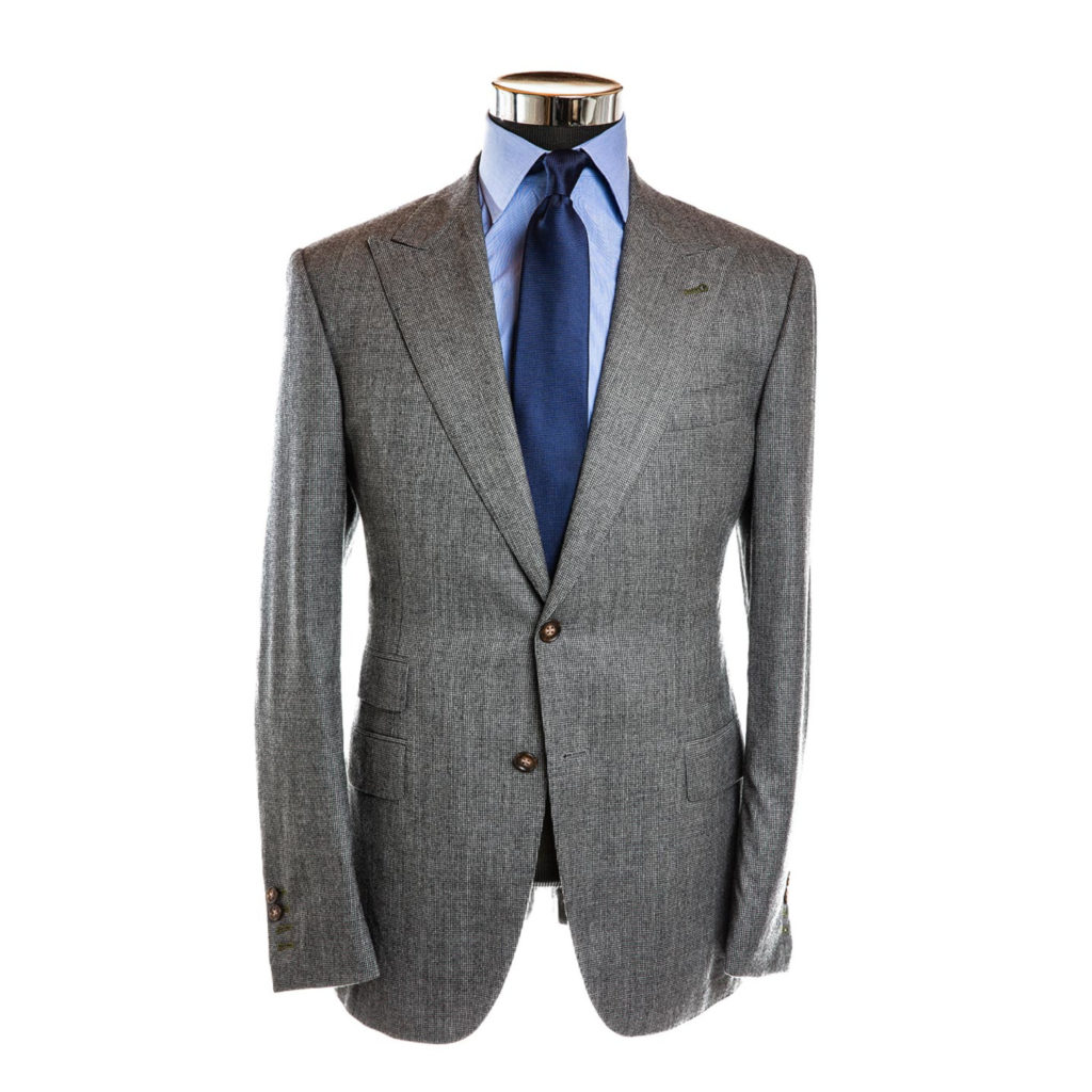 A heather grey houndstooth patterned suit jacket with a sky blue shirt and a cobalt blue tie on a white background