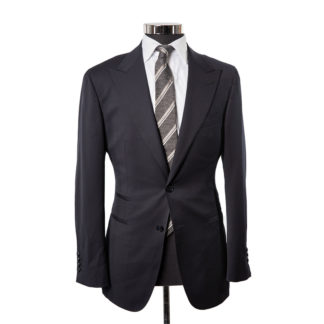 A deep midnight blue suit jacket posed on a body form with a wite shirt and grey striped tie on a white background