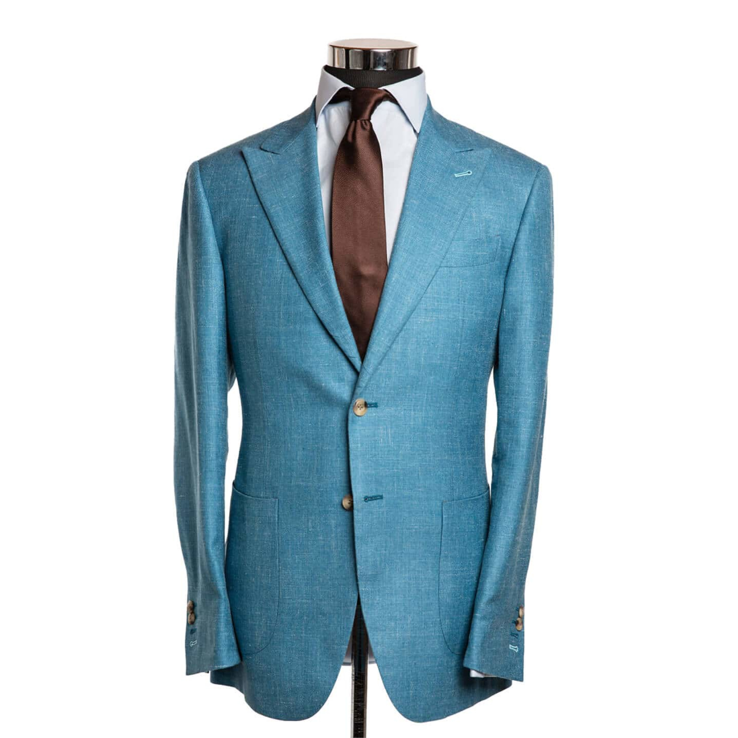 A bright sky blue suit jacket on a body form with a light blue shirt and a chocolate brown tie on a white background
