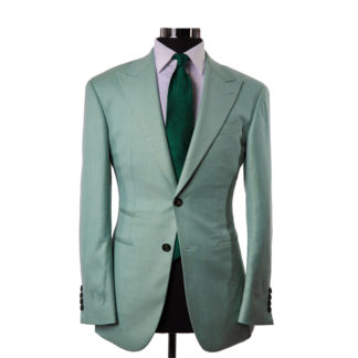 A light teal suit jacket on a body form with a white shirt and forest green tie on a white background