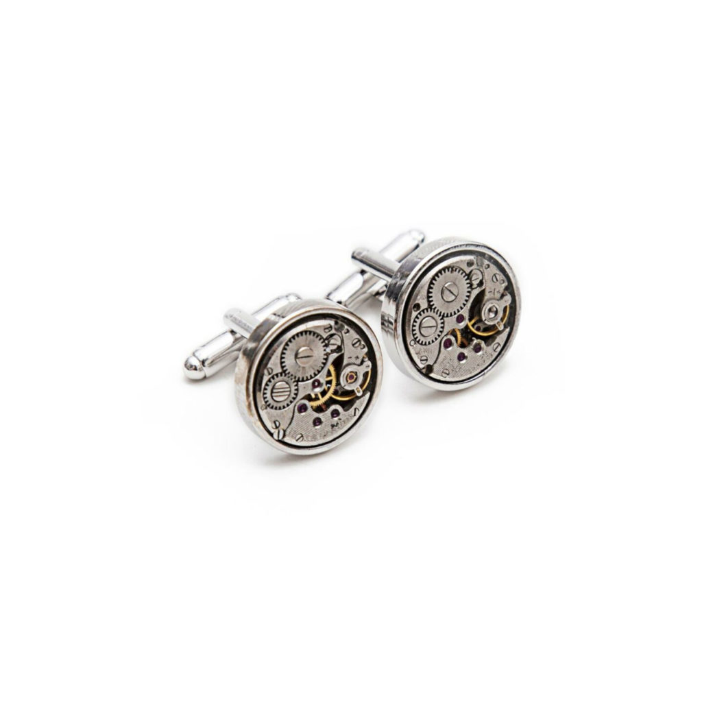 Round silver cufflinks with visible gears on a white background