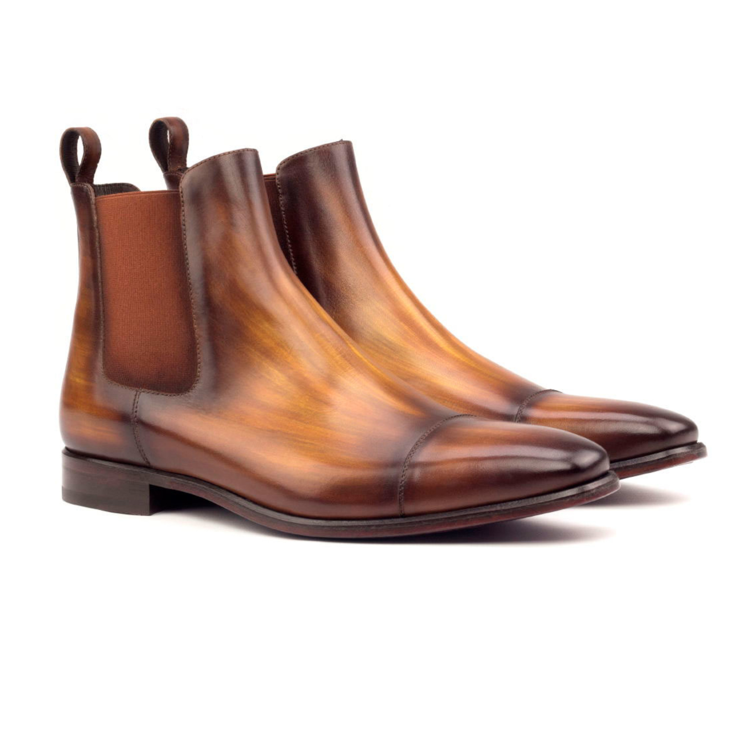 The Slingshot: Cognac Patina. Cognac patina Chelsea style ankle boots with rear finger loops on a white background