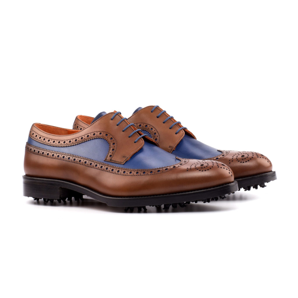 The Derby Golf Shoe: Blue/Calf . med brown painted calf + navy painted calf golf shoes with toe embellishments on a white background