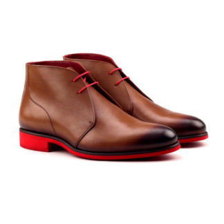 The Arborist: Painted Cognac. Front side view of med brown painted calf leather ankle style boots with red laces and red soles on a white background