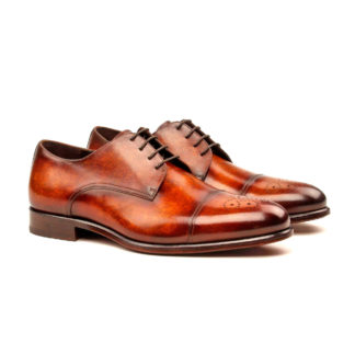 The Latus: Fire Patina. Front side view of fire patina leather men's dress style shoe with decorative toe cap and laces on a white background