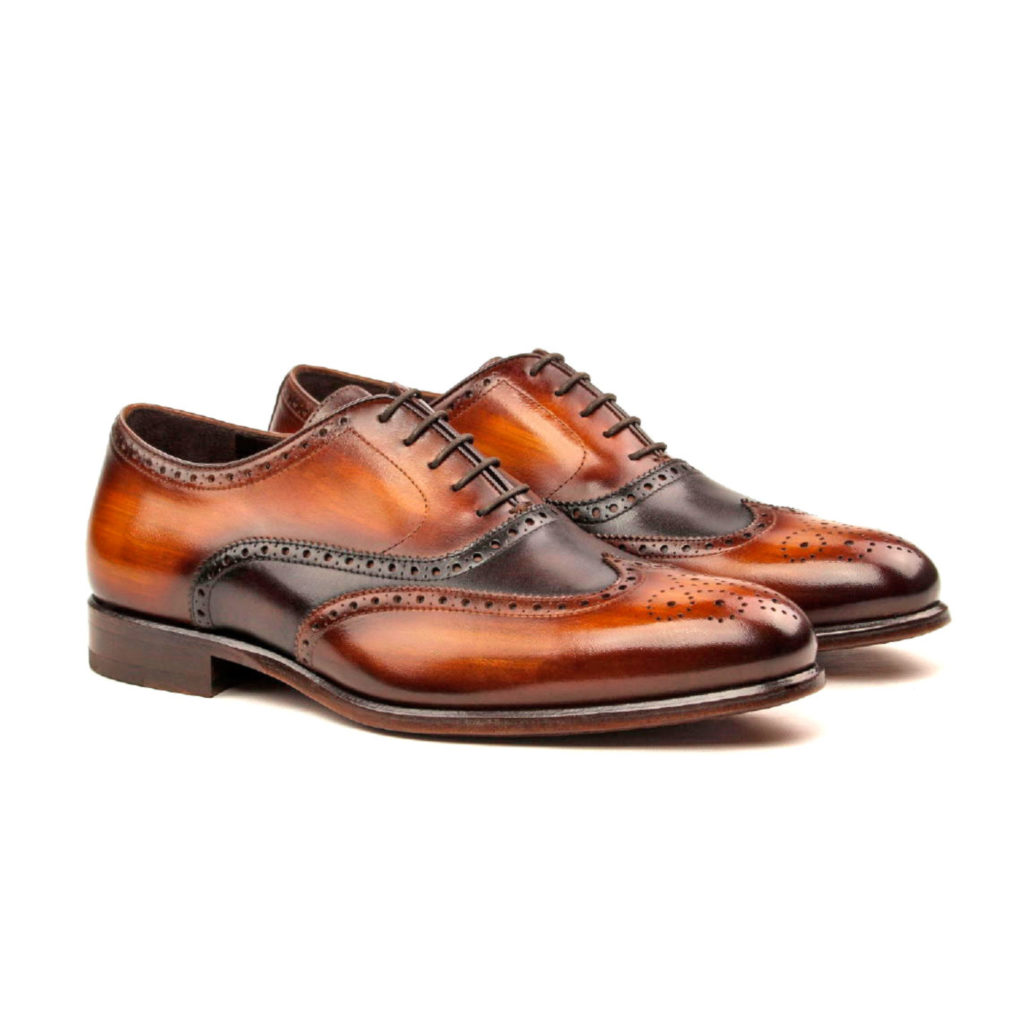 The Agent: Cognac/Brown Patina. Front side view of dark brown painted calf, cognac patina leather men's style lace up dress shoes with decorative toe cap on white background