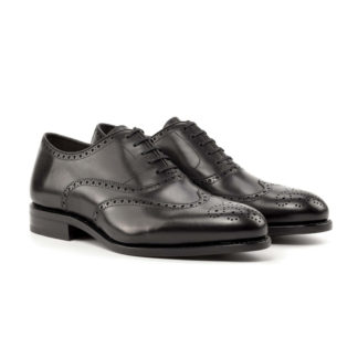 The Agent: Black Box Calf. Front facing view of black box calf leather men's style lace up dress shoes with decorative toe cap on a white background