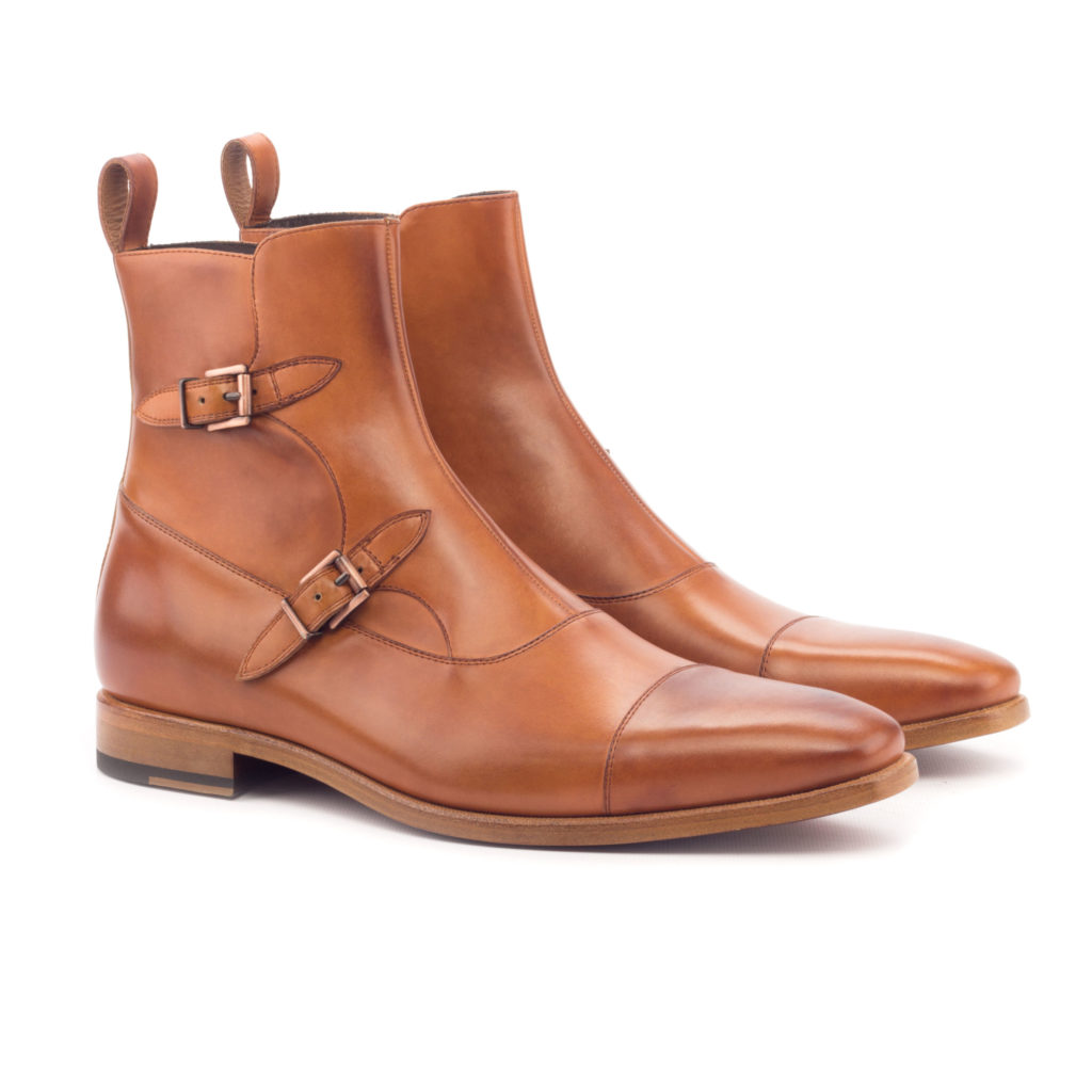 The Octavian: Cognac. Front side view of cognac painted calf leather ankle boots with 2 buckles on a white background