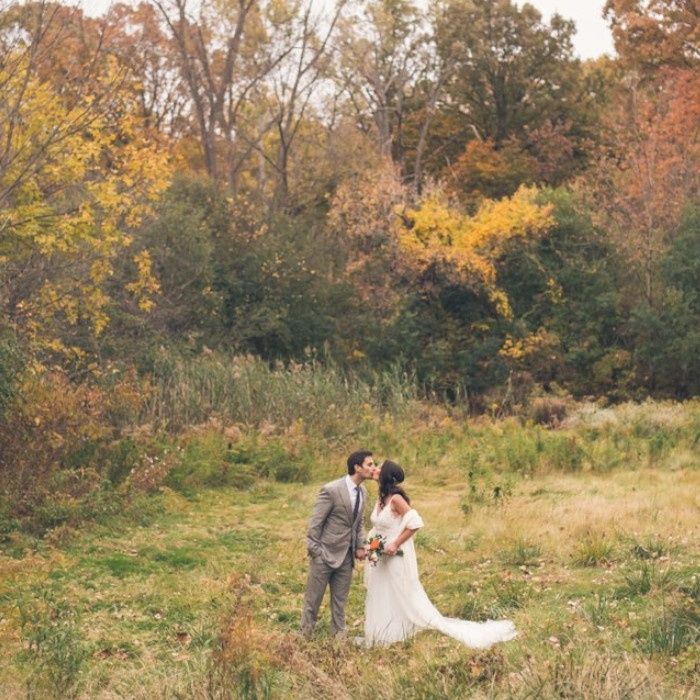 A posed wedding portrait of a man and a woman against colorful fall foliage.