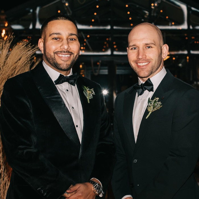 Two men wearing tuxedos and bow ties. they are smiling towards the camera.